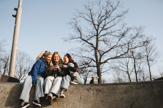 Teenage girls using phone in skatepark