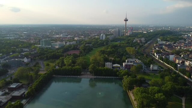 Drone shot of Aachener Weiher in Cologne, Germany - drone is reversing over the green belt, facing the Mediapark tower. Snippet could be used for travel related videos or Cologne movies.
