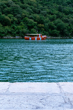 Red boat on water, with forest background, nearby shore.