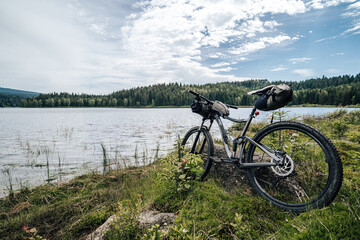Fototapeta na wymiar Bikepacking equipment on a mountain bike. Mountain bike with packed travel gear, bike packing gear ready to ride and camp outdoors.