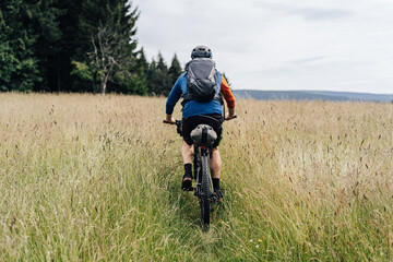 Bikepacking in the mountains. Man standing on a meadow with his bike and backpack ready for a...
