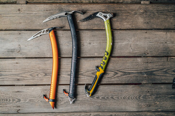 Detail photo of different ice climbing tools. Ice climbing gear, ice axe on a wooden background. Alpinist or mountaineer climbing equipment. - obrazy, fototapety, plakaty
