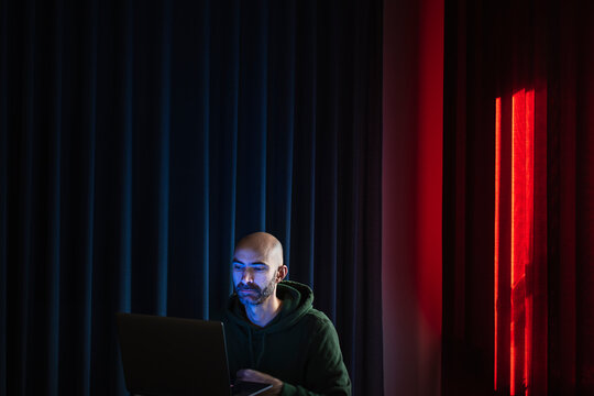 Man working on laptop in dark office