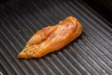 Lean healthy chicken breasts grilling over the hot coals on a portable BBQ with fresh tomatoes and potatoes for a healthy low fat meal