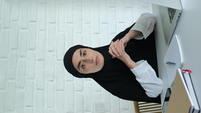 Office work for women of Islam. Vertical video with an Arab woman who works remotely on a laptop via the Internet. Muslim women's rights to work and use technology. Online learning.