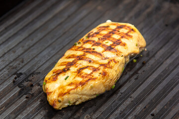 Lean healthy chicken breasts grilling over the hot coals on a portable BBQ with fresh tomatoes and potatoes for a healthy low fat meal