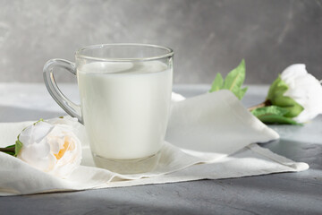 Obraz na płótnie Canvas A glass of milk on a napkin decorated with white flowers.