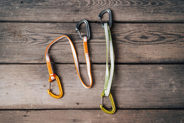 Close up detail photo of carabiners and slings. Climbing gear or equipment on a wooden background. Color biners for rock climbing. Sport climbing equipment.