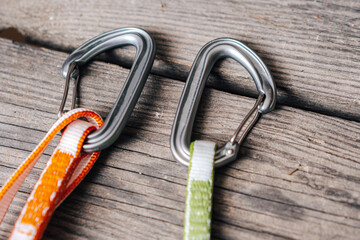 Close up detail photo of carabiners and slings. Climbing gear or equipment on a wooden background. Color biners for rock climbing. Sport climbing equipment.