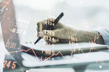 Multi exposure of abstract statistics data hologram interface with hand writing in notepad on background with laptop, computing and analytics concept