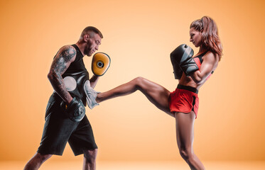 Athletic woman in red shorts and top is boxing with a trainer. Boxing and mixed martial arts...