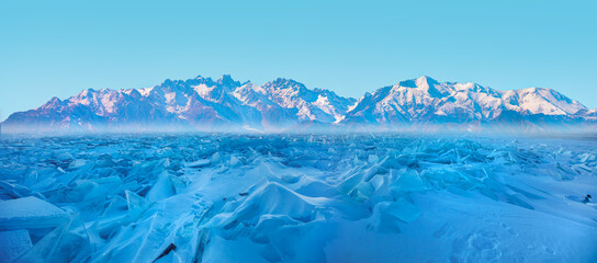 Beautiful winter landscape of frozen Lake Baikal at sunrise - Snowy ice hummocks with transparent blue piles of ice - Baikal Lake, Siberia 