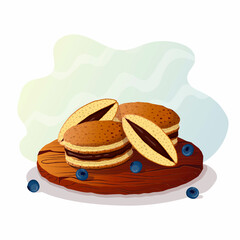 Japanese pancakes - dorayaki on a wooden plate or tray, whole and cut with chocolate filling and blueberries.