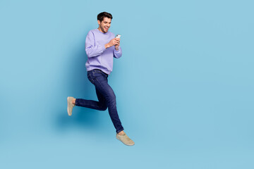 Fototapeta premium Photo of positive guy jump high use smart device hurry network discounts isolated blue pastel color background