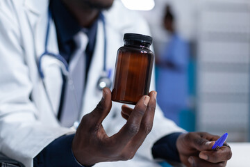 Close up of clinic physician specialist holding a bottle of pharmaceutical analgesic in personal cabinet. Hospital doctor holding prescribed antibiotic while presenting patient side effects