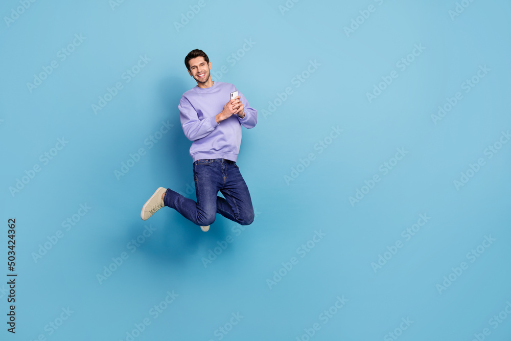 Poster photo of millennial blogger guy jump use device enjoy network ads apps isolated pastel blue color ba
