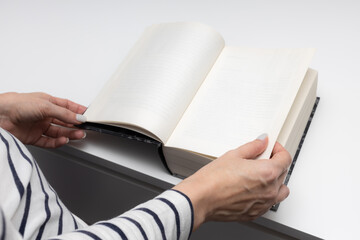 a woman opens a book with her hands on the first page