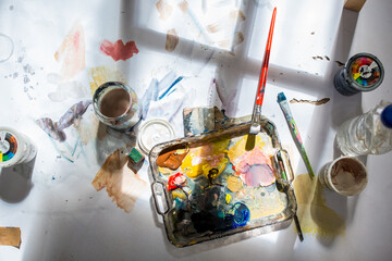 Palette and paint brush in artist hands. Artist paints oil picture with paint brush in hand palette...