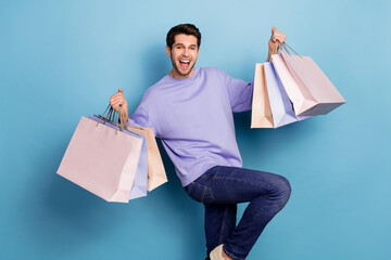 Photo of impressed millennial brunet guy hold bags yell wear sweater jeans isolated on blue color...