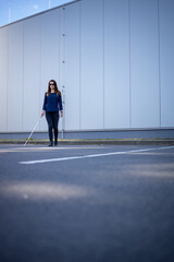 Blind woman walking on city streets, using her white cane to navigate the urban space better and to get to her destination safely