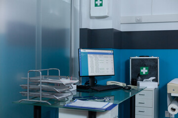 Empty doctor office with nobody in it equiped with medical equipment having work computer on desk...