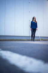 Blind woman walking on city streets, using her white cane to navigate the urban space better and to...