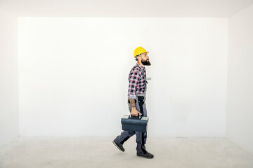 A handyman walking in unfinished apartment with his toolbox. A worker at his workplace.