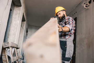 A repairman checking on wooden beam at building in construction process.