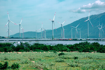 Fototapeta na wymiar Windmill farm with several wind turbines on hills landscape to generate renewable electricity. Green eco earth day energy concept to reduce global warming and climate change