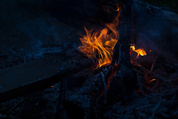 Bright orange bonfire on night camp on dark blue indigo color beach, contrast. Night bonfire on...