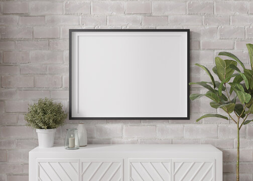 Empty horizontal picture frame on white brick wall in modern living room. Mock up interior in minimalist, contemporary style. Free space for your picture, poster. Console, candle, plant. 3D rendering.