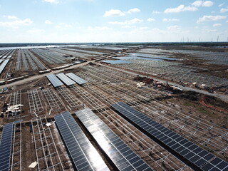 Aerial view of solar power plant under construction on a dirt field. Assembling of electric panels...