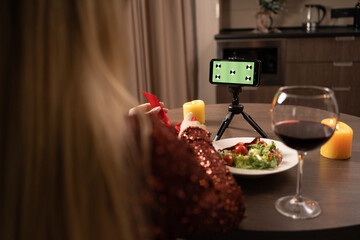 View your smartphone screen over your shoulder. Young woman makes a video call on a green screen of a smartphone with tracking markers. Chrome plated key background