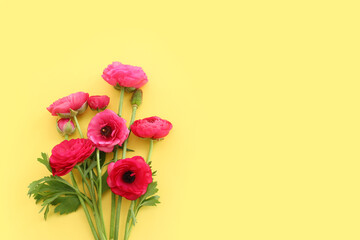 Top view image of pink flowers composition over yellow background