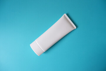 A blank white squeeze bottle plastic tube on blue background. Packaging of cream, lotion, gel, facial foam or skincare. Cosmetic beauty product branding mock-up. Copy space