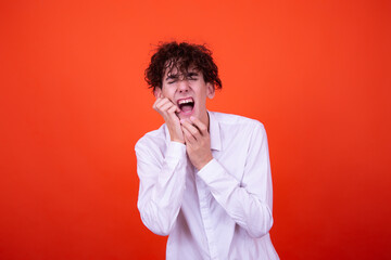 Emotions of a young attractive guy. Orange background.