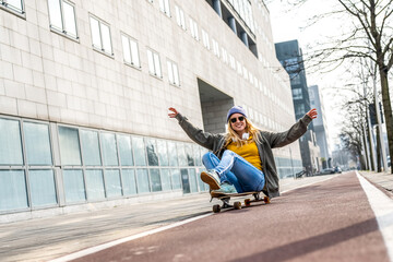 Athetic young woman riding longboard and sitting on it, urban background, yellow shirt and blue jeans, generation z female crazy lifestyle - Powered by Adobe