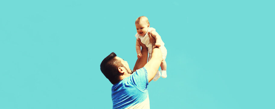 Happy Father Playing With Baby Raising Up On Blue Sky Background