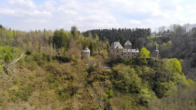 Aerial shot of Reinhardstein Castle in forest landscape with waterfall in the Warche Valley. Highest positioned castle of Belgium.