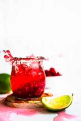 Splash Foto von einem Sommer Getränk mit firischen Himbeeren, Soda und Limetten auf einem weißen Tisch. Spritzig, kalt.
