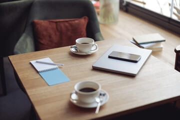 Work in cafe. Table with two white coffee cups. Cozy place. laptop and smartphone. Business concept.