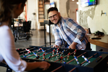 Colleagues having fun at work. Businessman and businesswoman playing table soccer.