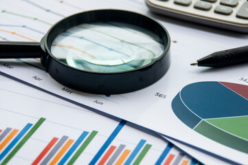 Analysis of data, chart and graphs with calculator and magnifying glass. Business finances concept.