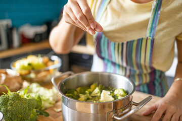 Young woman adding spices to lunch