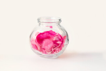 Pink rose petals in a glass container.Ingredients for natural cosmetics, oils and jams, on white background