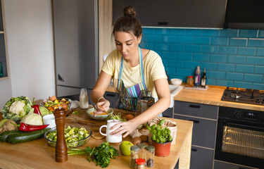 Young woman adding spices to lunch