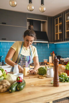 Young woman cutting cheese on wooden board