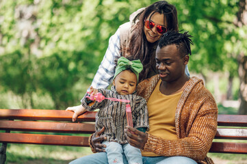 Diverse family blowing soap bubbles in park