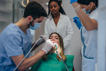Woman patient in dental clinic being examined by a male dentist