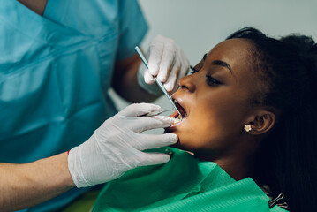 Dentist providing dental care treatment to a african american female patient